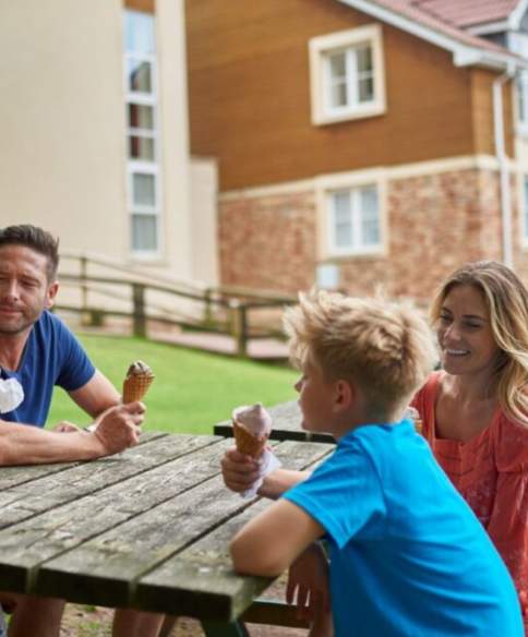A fmaily eating ice cream on a bench outside Wookey Hole hotel - Credit Wookey Hole